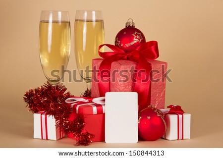 Christmas gifts, toys, tinsel, champagne and empty card, on a beige background