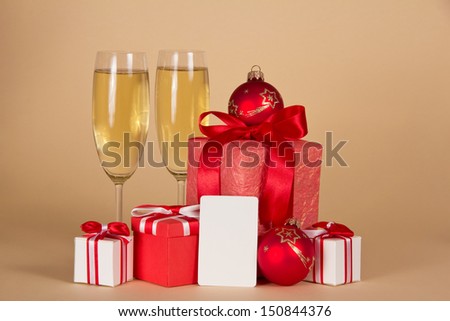 New Year\'s gifts, wine glasses with champagne and an empty card for the message, on a beige background