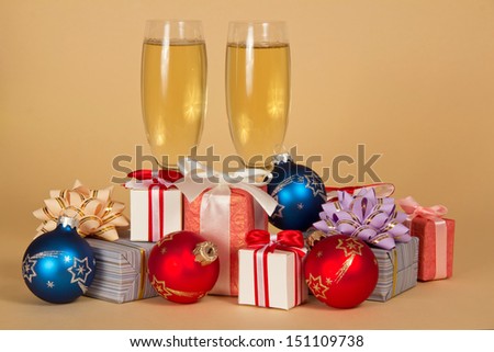 Set of different gift boxes, toys and wine glasses with champagne on a beige background