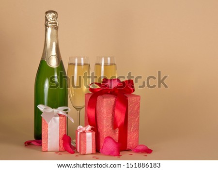 Bottle and wine glasses with champagne,  three gift boxes with a ribbon and a bow, rose petals on a beige background