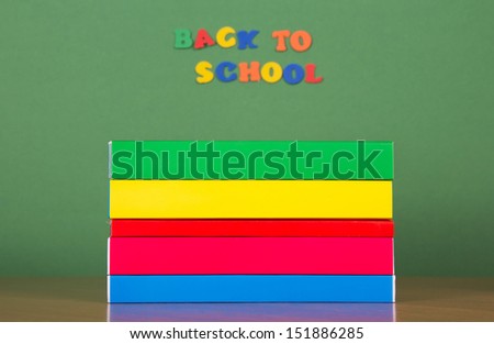 Stack of books and set of plastic letters, on a green background