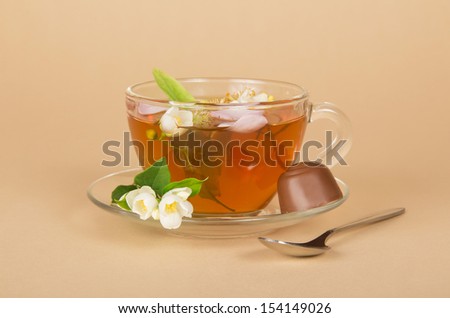 Cup of flower tea and the chocolate, on a beige background