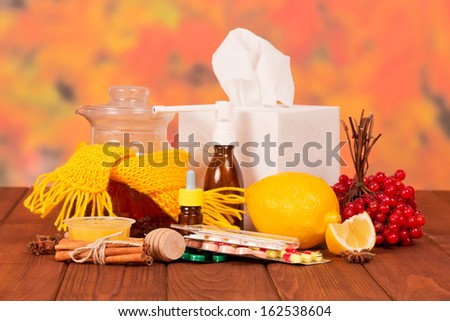 Various cold medicines on a table against autumn foliage
