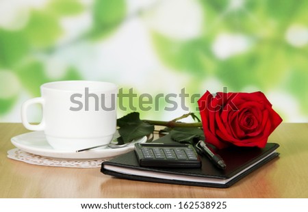 Table in cafe with a cup of coffee, rose and business notebook