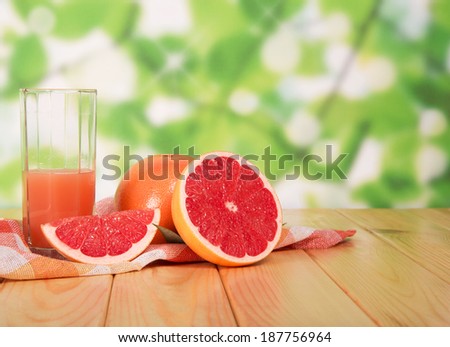 Glass of grapefruit juice and sliced ??on table in yard