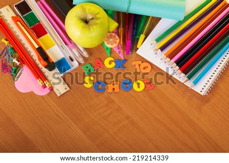 Blank sheets, set of color pencils and paint for drawing, a ruler and apple on a table