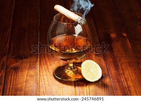 Glass of cognac with lemon and cigar