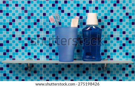 Toothpaste and toothbrushes on bathroom shelf