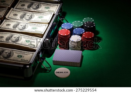 Poker chips and dollar bills in case on green background