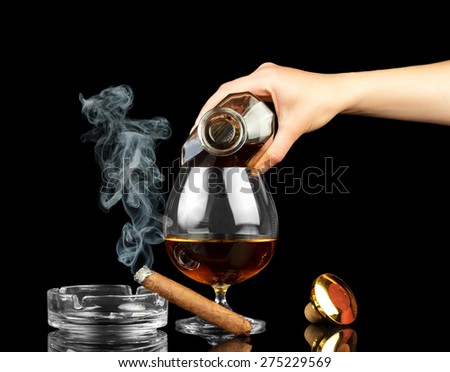 Cognac in bottle, glass and cigar on black background