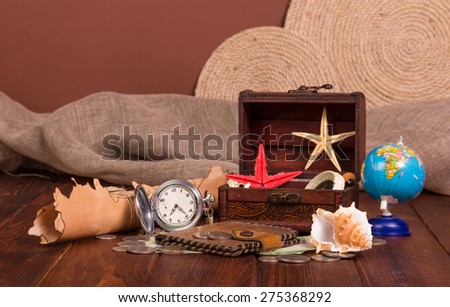 Old compass, treasure chest, knife, money, globe and starfishes on wooden table