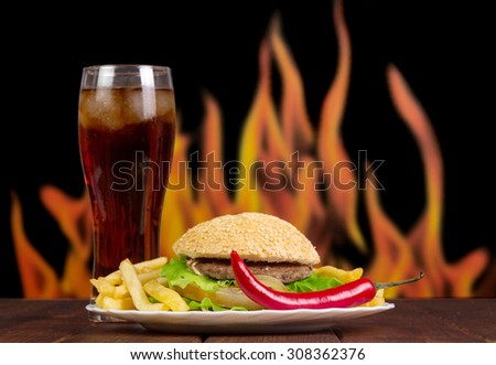 Fast food set of a burger, french fries and cola on flames background