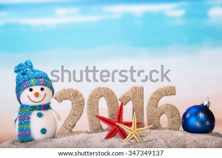 New year sign with starfishes on sandy beach and snowman