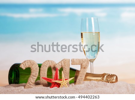 Figures 2017, a bottle of champagne and glass, starfish in the sand against the sea.