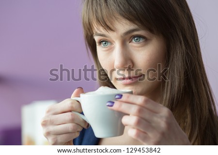 Beautiful girl with a white cup of coffee looking into the distance