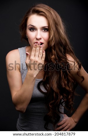 portrait of a girl in a gray T-shirt with a hand on the face. on a gray background