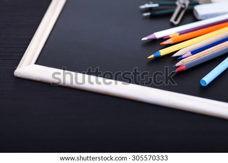 Black, wooden table top view of the artist. On the table laid out creative stationery items to draw, paint, chalk board, stickers. For convenient and fast work of the artist.