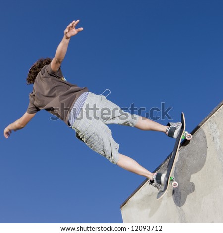 Teen boy does tricks in the half pipe at a skate park