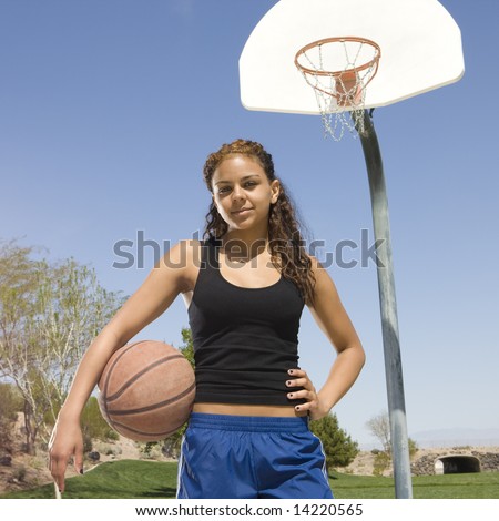 Teen girl with basketball hangs out at a basketball court