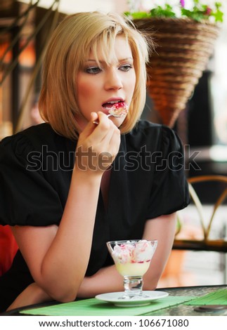 Young woman eating an ice cream at sidewalk cafe