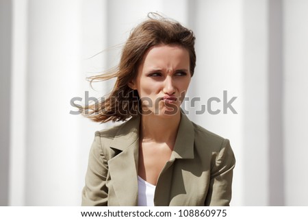 Angry young woman against a white wall