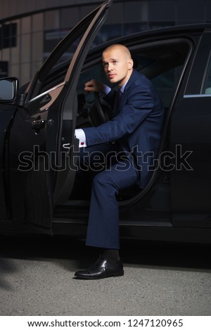 Young handsome businessman wearing dark blue suit sitting in his car