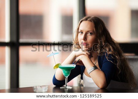 Sad young woman with cocktail at restaurant