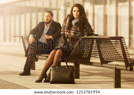 Young fashion couple in conflict on city street Stylish trendy man in classic black coat and woman wearing fox fur jacket