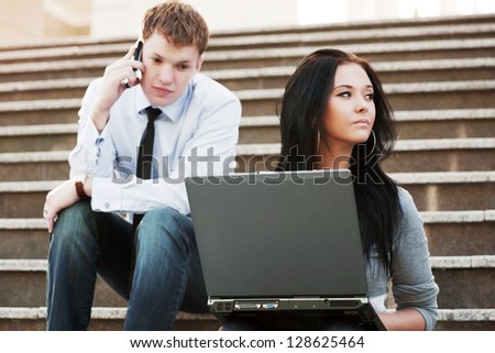 Young business people with laptop sitting on the steps