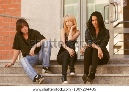 Young fashion men and women sitting on steps Stylish trendy male and female models