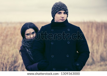 Happy young fashion couple in love walking outdoor Stylish man and woman wearing classic coats beanie and scarf