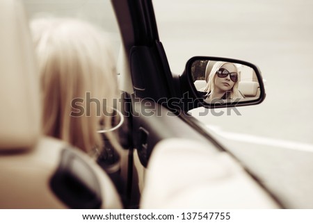Young woman looking in the car mirror Young woman looking in the car mirror