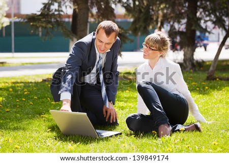 Young business people with laptop in a city park