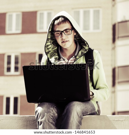 Young man using laptop on the sidewalk