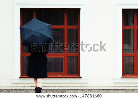 Woman with umbrella looking through the window