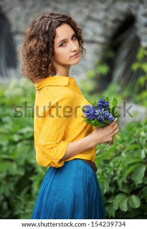 Sad young woman with bouquet of flowers