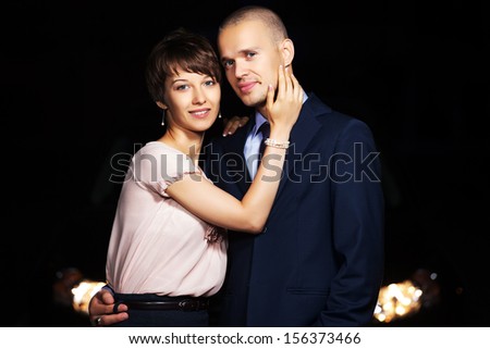 Young couple in the night in front of car headlights