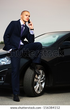 Young business man calling on the phone at the car