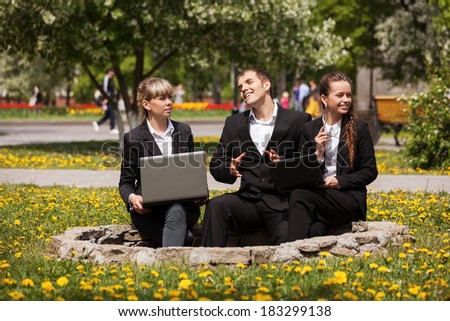 Young business people using laptop in a city park