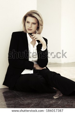 Young business woman with a mobile phone sitting at the wall
