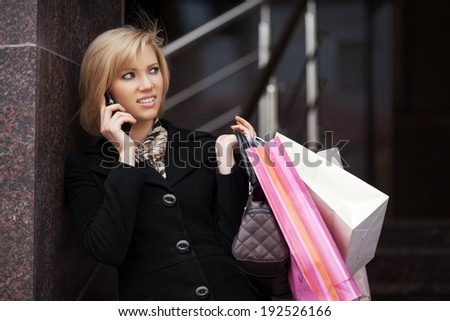 Blond woman with shopping bags calling on the phone