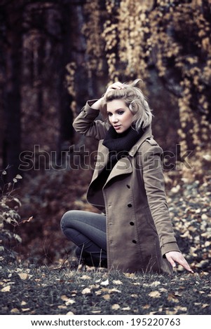 Young fashion blond woman in autumn forest