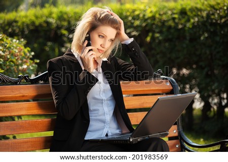 Young business woman with laptop calling on the cell phone