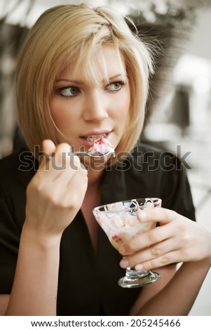 Young woman eating an ice cream at sidewalk cafe