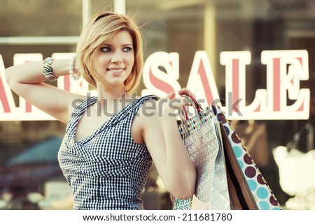 Happy young fashion woman with shopping bags at the mall windows