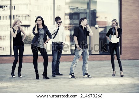 Group of young fashion men and women calling on the phones