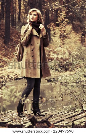 Happy young fashion woman with handbag in autumn forest