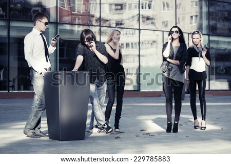 Group of young fashion men and women calling on the phones