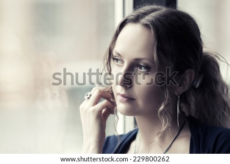 Sad beautiful woman looking out window