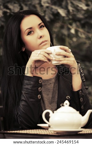 Young fashion woman in leather jacket drinking a tea